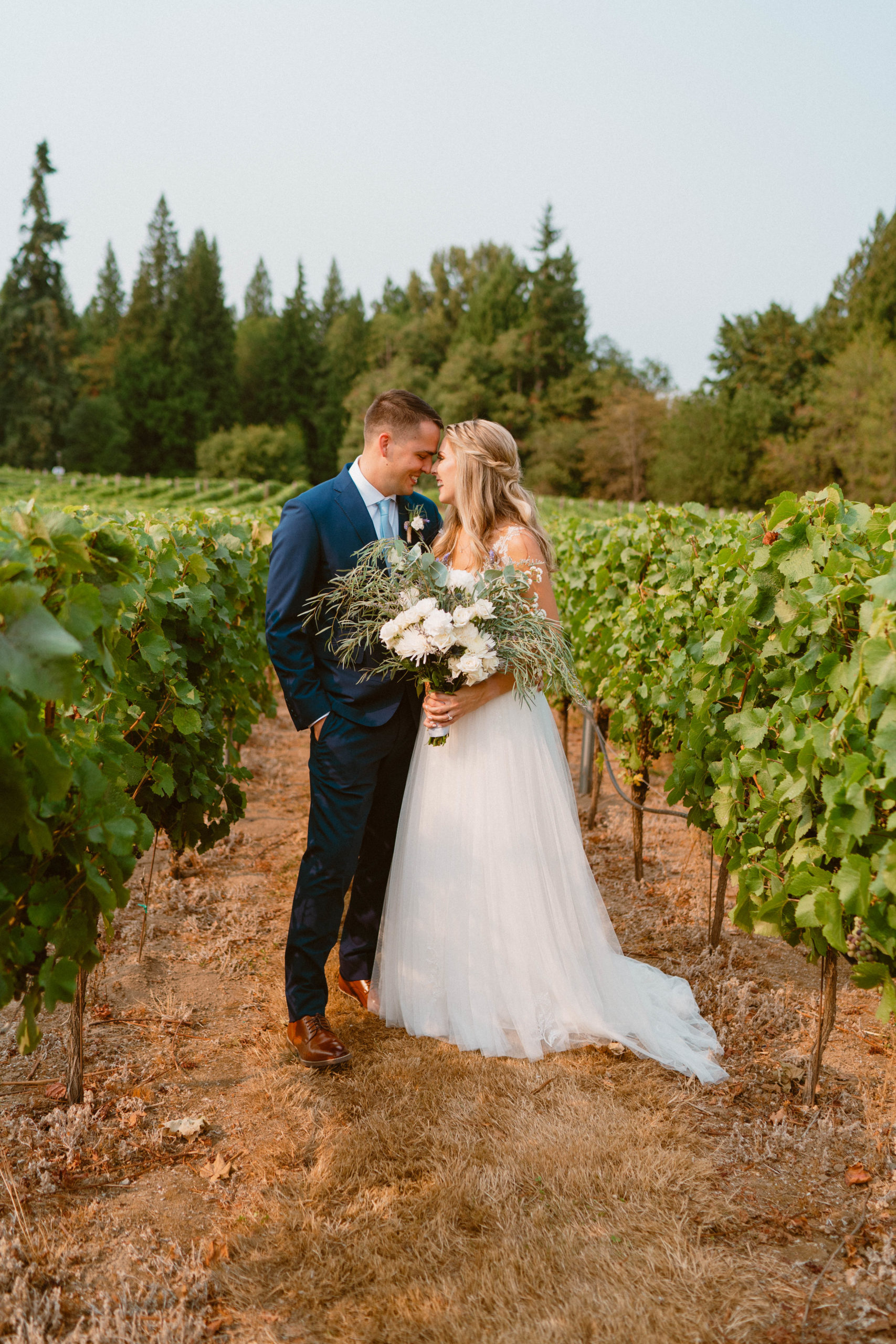 bride and groom looking into each others eyes in the middle of a vineyard moments before their wedding ceremony